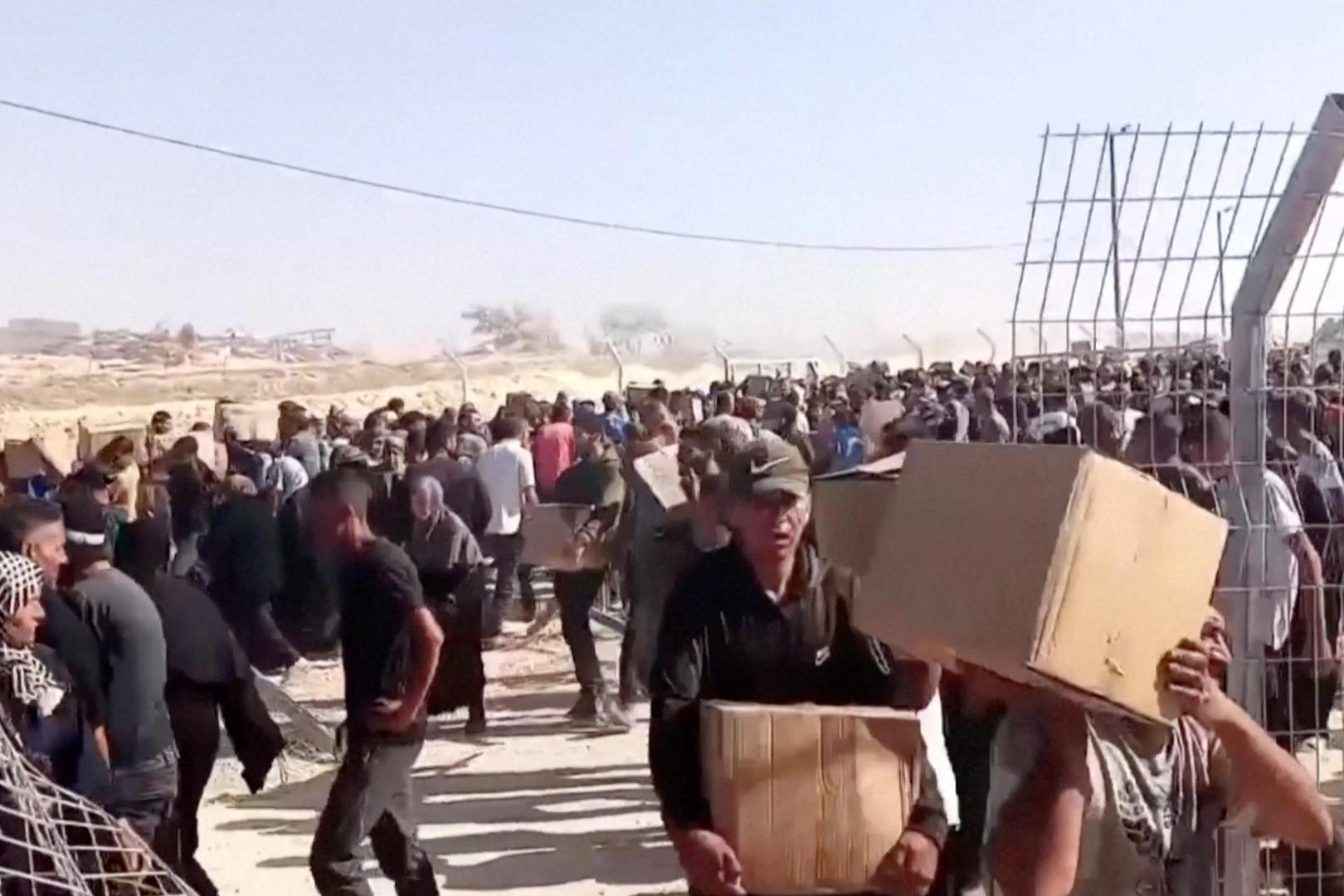 Palestinians walk back carrying aid boxes, in Rafah, in the southern Gaza Strip, May 27, 2025, in this screengrab from a video. Reuters TV/via REUTERS 