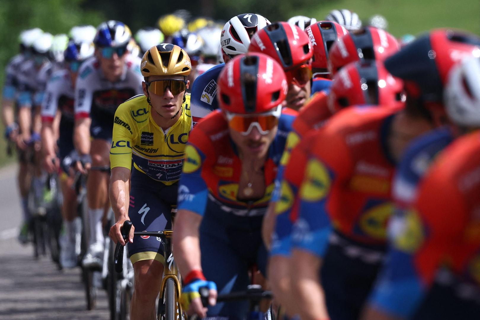 Soudal Quick-Step's Belgian rider Remco Evenepoel (C) wearing the overall leader's yellow jersey cycles with the pack during the 5th stage of the 77th edition of the Criterium du Dauphine cycling race, 183 km between Saint-Priest and Mâcon, on June 12, 2025. (Photo by Anne-Christine POUJOULAT / AFP)